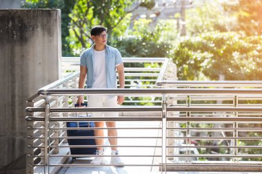 Bagajı olan Asyalı yakışıklı adam tatil zamanı yürüyor, seyahat konsepti..