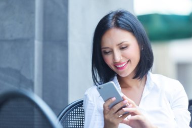 Kafede akıllı telefon kullanan genç bir kadın.