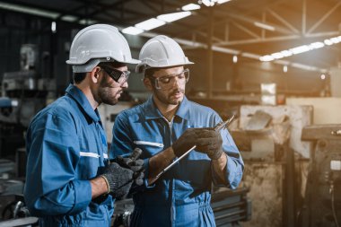Üniforma giyen mühendisler fabrikada tamirat yapıyor..