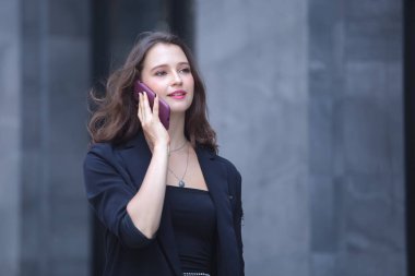 İş kadını şehir caddesinde cep telefonundan arıyor..