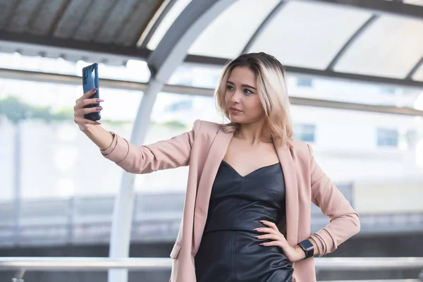 年轻的女商人用智能手机开心地在城市里有视频通话和照片自拍 — 图库照片
