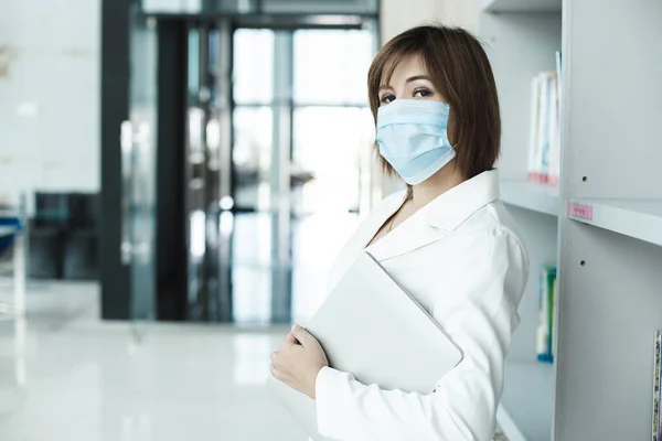 共同作業スペースでノートパソコンとの感染ウイルスを防ぐための医療面マスクを身に着けているアジアの女性 コロナウイルス Covid — ストック写真