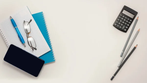 Stay at home white background flatlay. Home office smartphone blue notebook pencils pen top view template long banner. Copy space backdrop mock up design. Distance education creative work concept.