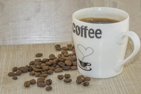 Taza de café y granos de café tostados sobre una base de madera — Foto de Stock