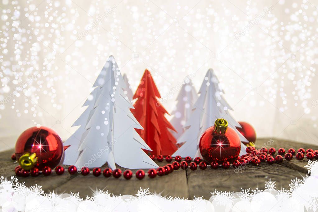 Christmas origami trees on a wooden surface with red beads and red shiny balls