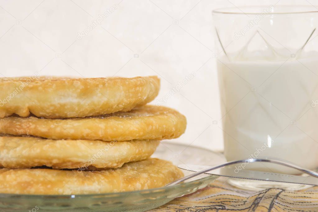 Crispy, fried, tasty dough on a plate and glass of yogurt with a white background