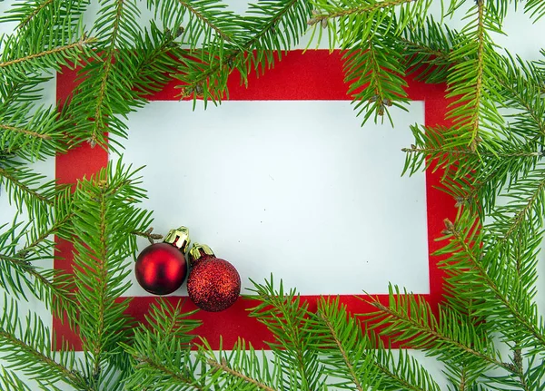 Noel 'deyiz! Beyaz arkaplanda kırmızı çerçeve ve Noel ağacı dalları.