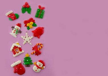 Noel 'deyiz! Pembe arka planda renkli tatil süslemeleri. Üst görünüm.