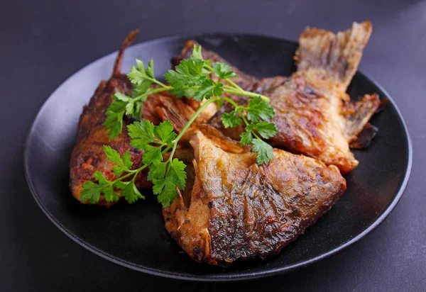 Pescado frito en plato negro —  Fotos de Stock