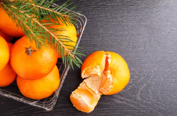 Tangerines in a metal basket with a branch of a Christmas tree — Stock Photo, Image