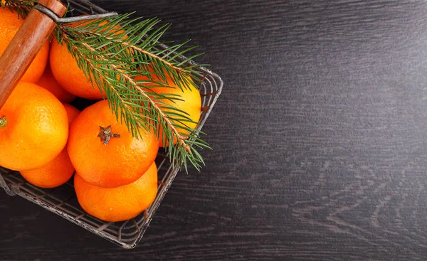 Tangerines in a metal basket with a branch of a Christmas tree — Stock Photo, Image