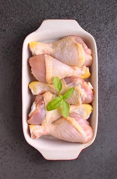 Pernas de frango cru em um prato vermelho . — Fotografia de Stock