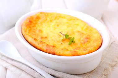 Süzme peynir güveç beyaz çanağı nane, Beyaz ahşap zemin üzerinde süslenmiş. Seçici odak.