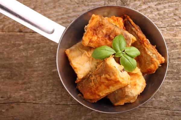 bir tavada kızarmış balık hake fesleğen ile dekore edilmiştir.