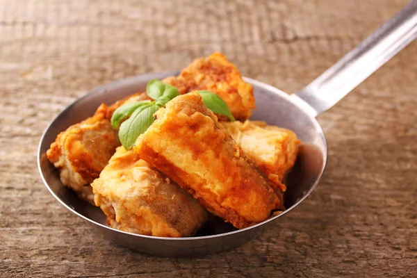 bir tavada kızarmış balık hake fesleğen ile dekore edilmiştir.