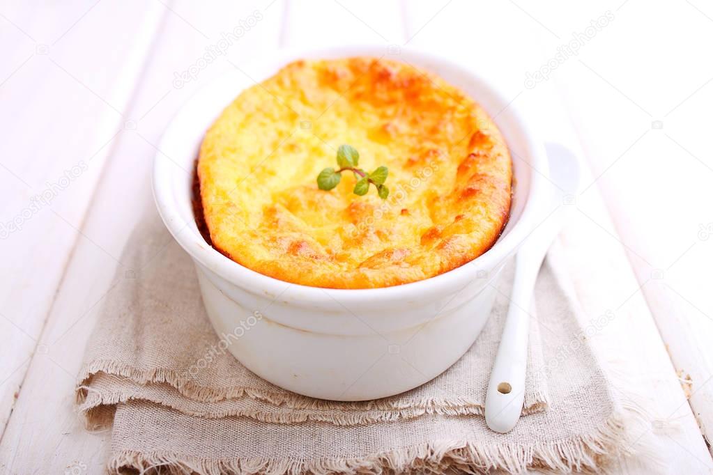 Cottage cheese casserole in white dish decorated with mint, on a white wooden background. Selective focus.