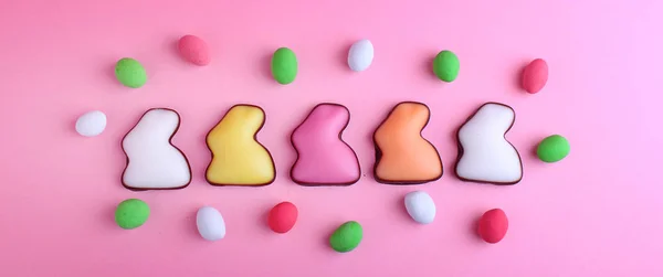 ピンクの背景でお菓子とウサギの形をしたカラフルな生気のないクッキー — ストック写真