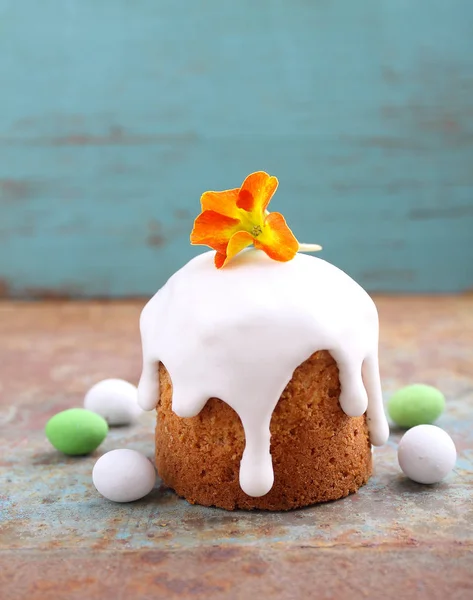 Easter cake decorated with flower and candies shaped eggs on rusty surface