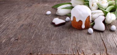 Tavşan ahşap arka plan üzerinde taze Beyaz Laleler, Paskalya kek ve sırlı çerezler ile Paskalya kompozisyon şeklinde