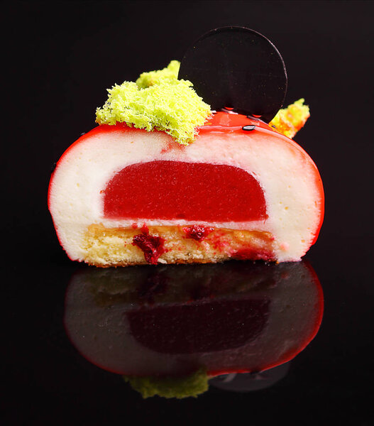 Close up of halved colorful strawberry cake on black background