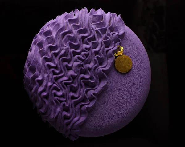 lilac round mousse cake decorated with molecular sponge cake on a black background, top view