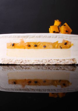 Siyah arka planda moleküler sünger kekiyle süslenmiş beyaz yuvarlak kremalı pasta.