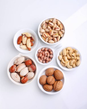 Beyaz arka planda beyaz bir seramik kasede fındık karıştır. Ceviz, fındık, ceviz, fıstık, Brezilya fıstığı ve fıstık. Üst görünüm. 