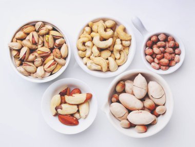 Beyaz arka planda beyaz bir seramik kasede fındık karıştır. Ceviz, fındık, ceviz, fıstık, Brezilya fıstığı ve fıstık. Üst görünüm. 