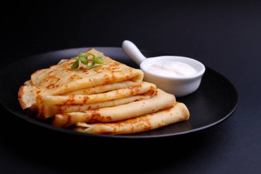 Siyah arka planda ekşi kremalı krep.