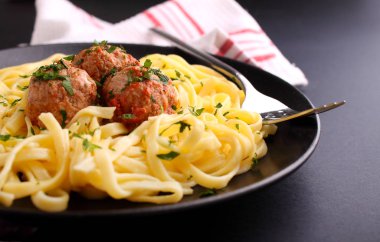 Siyah arkaplanda köfteli makarna.