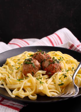 Siyah arkaplanda köfteli makarna.