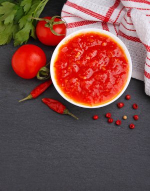 Spicy vegetable sauce of tomatoes and peppers on a dark background