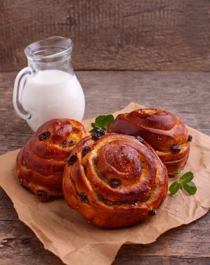 Kuru üzümlü çörekler ve arka planda süt, taze hamur işleri..