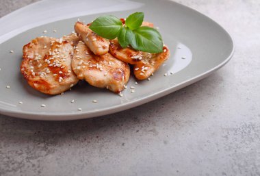 Susam tohumu ve fesleğenle dekore edilmiş soya soslu kızarmış tavuk.