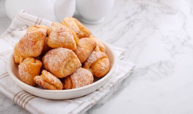 Mermer bir arka planda taze pişmiş süzme peynir ve şeker kurabiyeleri (üçgenler, açılar). Kaz ayağı..