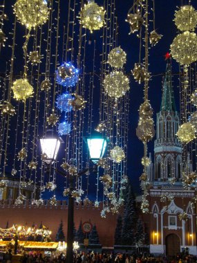 Kremlin Kulesi ve Kremlin Duvarı 'nın arka planında aydınlanma var. Yeni yıl arifesi. Parlayan çelenkler.