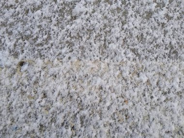 Beton bloğun yüzeyi kar ile hafifçe tozludur.