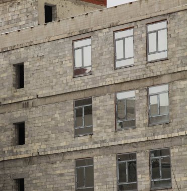 Pencereler boş ve inşaat halindeki bir binanın cephesinde çerçeveler var