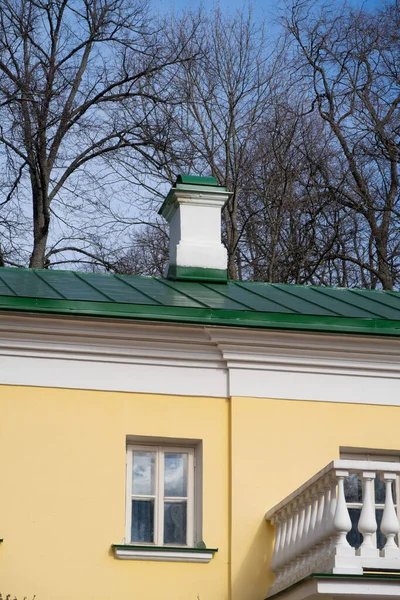 緑の屋根の上に白い煙突と黄色の壁に白いバラスターと窓 — ストック写真