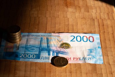 Rus banknotu 2000 ruble ve sabah güneşinde bir yığın bozuk para.