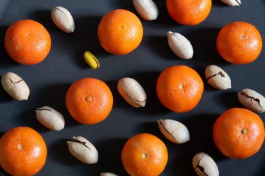 Mandalina ve ceviz, siyah arka planda yatay çapraz yerleşim ve bir şam fıstığı