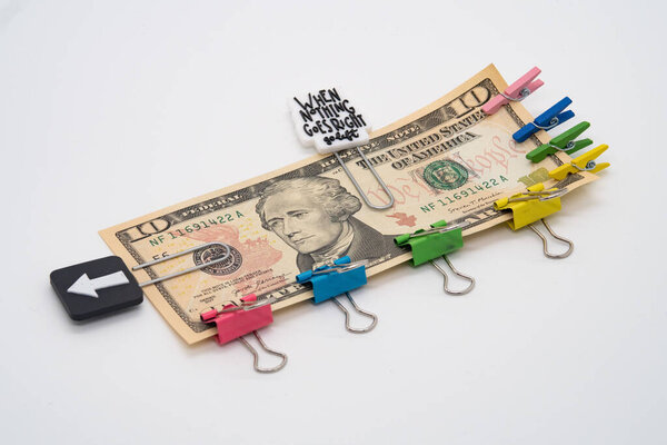 Десять долларов купюры и разноцветные скрепки и прищепки с девизом, когда ничего не идет правее идти влево, обязательства
