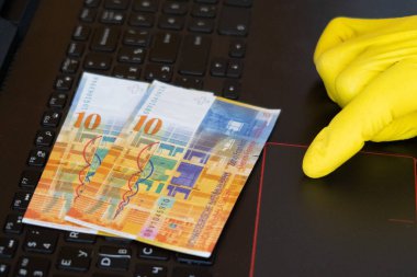İsviçre banknotları, on frank, eldiven, dokunmatik parmak, klavye. Kopya yazma, para siparişi için makaleler yazma, karantina sırasında internet üzerinde çalışma