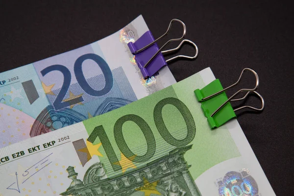 Twenty Euro banknotes, one hundred euros, colored paper clips on the color of banknotes, purple and green