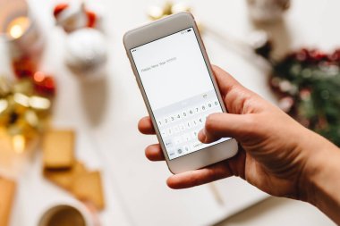 Bir akıllı telefon tutarak ve mutlu yeni yıl yazma el 
