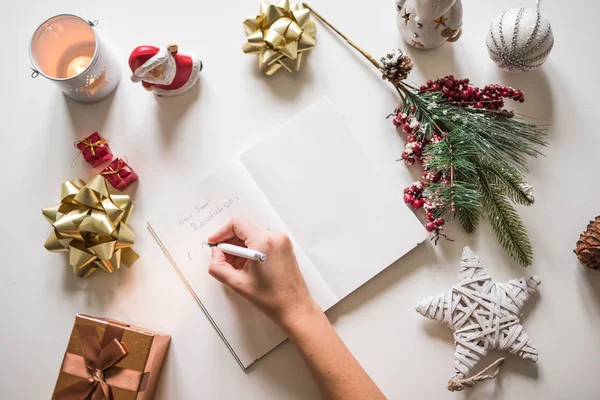 New year resolutions written with a hand on notebook with new years decorations — Stock Photo, Image