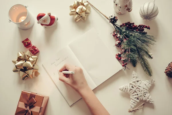 Nyårslöften som skrivs med en hand på anteckningsboken med nyårs dekorationer — Stockfoto