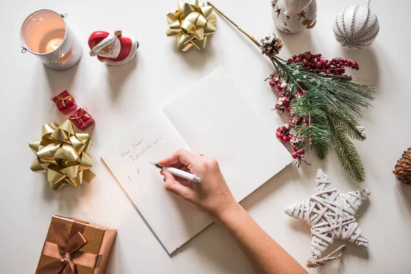 Nyårslöften som skrivs med en hand på anteckningsboken med nyårs dekorationer — Stockfoto