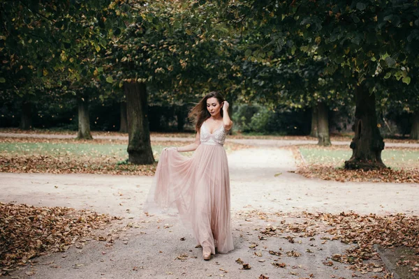 Hermosa mujer en vestido de noche rosa largo caminar camino en el parque —  Fotos de Stock