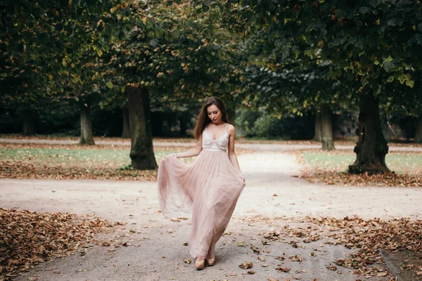 Bela mulher em longo vestido de noite rosa caminhando caminho no parque — Fotografia de Stock